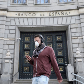 Un hombre con una mascarilla pasa junto a las oficinas del Banco de España, en Barcelona. REUTERS/Nacho Doce