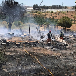 Miembros de los servicios de bomberos extinguen las llamas tras un incendio declarado en un asentamiento chabolista de Lepe, Huelva. - EFE