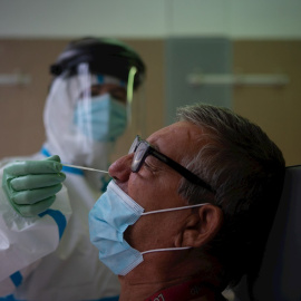 Una profesional sanitaria realiza una prueba PCR a un paciente. EFE/Enric Fontcuberta