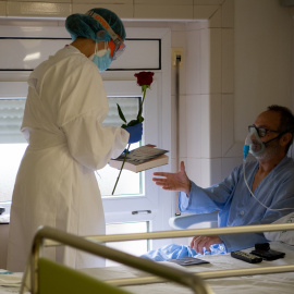 Una professional de l'Hospital Clínic lliura a un pacient ingressat una rosa i un llibre per Sant Jordi, en la pandèmia de coronavirus. Francisco Ávila / Hospital Clínic