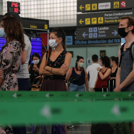 Diversos passatgers de l'aeroport del Prat amb mascaretes fent cua per facturar l'equipatge en el dia de la reobertura de la T2. GEMMA SÁNCHEZ / ACN