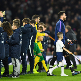 Un niño acompañando al portero y capitán del Tottenham Hotspur, Hugo Lloris. / Reuters