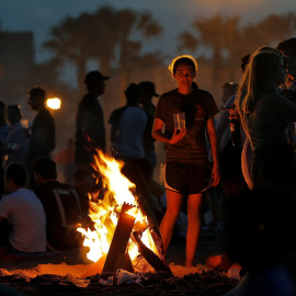 Una joven observa las llamas de la hoguera que ha encendido junto a un grupo de amigos para celebrar la Noche de San Juan | EFE