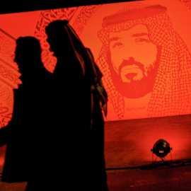 Dos jóvenes pasan junto a un retrato del príncipe heredero de Arabia Saudí Mohammed bin Salman,en una de las principales avenidas de Riad. AFP/FAYEZ NURELDINE