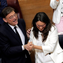 12/06/2019.- El candidato a la reelección como president de la Generalitat, Ximo Puig, y la vicepresidenta en funciones, Mónica Oltra, se dan la mano tras su discurso de investidura en Les Corts Valencianes. EFE/Manuel Bruque