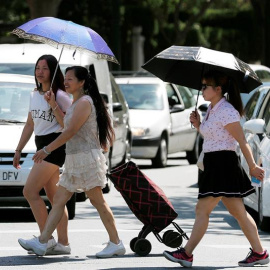 Tres mujeres se protegen del sol y del calor con sombrillas. /EFE