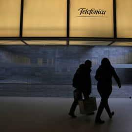 Dos personas pasan bajo el logo de Telefónica en la sede de la operadora en el distrito de Las Tablas de Madrid. REUTERS/Juan Medina