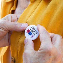  Una mujer coloca una chapa a otra, en una concentración enmarcada en la campaña #MamáEstáCastigada, frente a la Delegación del Gobierno, a 29 de mayo de 2021, en Badajoz, Extremadura (España). / JAVIER PULPO / Europa Press