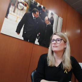 Elsa Artadi durant l'entrevista realitzada al Parlament amb una foto de Josep Rull i Jordi Turull al fons.