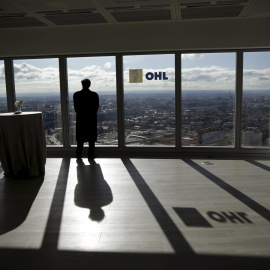 Un hombre mira a través de un ventanal de la sede en Madrid de la constructora OHL. REUTERS/Andrea Comas