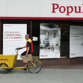 Un repartidor pasa ante una oficina del Banco Popular en Barcelona. EFE/Andreu Dalmau