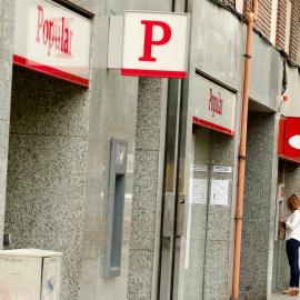 Una mujer usa un cajero automático en una oficina del Banco Santander junto a una sucursal del Banco Popular. REUTERS/Albert Gea