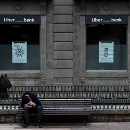 Un hombre sentado frente a la sede de Liberbank en Oviedo. REUTERS/Eloy Alonso