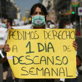 Una mujer sujeta una pancarta en la que se lee 'Pedimos derecho a 1 día de descanso semanal' durante una manifestación de los médicos internos residentes (MIR) en Madrid. /Europa Press