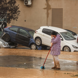  Una mujer realiza labores de limpieza junto a vehículos destrozados tras el paso de la DANA por el barrio de La Torre de València - EP