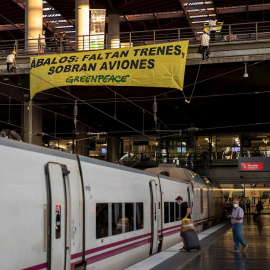 Activistas de Greenpeace han desplegado esta mañana una pancarta sobre las vías de Atocha para denunciar la falta de trenes en un verano marcado por la crisis de la covid-19. Bajo el texto "Ábalos: faltan trenes, sobran aviones". EFE/Pablo Blázquez