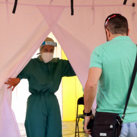 Una sanitària obrint una carpa del SEM a Terrassa mentre un noi accedeix a fer-se la prova PCR. GEMMA SÁNCHEZ / ACN