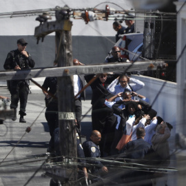 Las transeúntes  están siendo evacuados con las manos por encima de sus cabezas por orden de la policía en el área de un incidente de tiroteo en una instalación de United Parcel Service (UPS) en San Francisco, California, EE.UU. 14 de junio de 2017. 