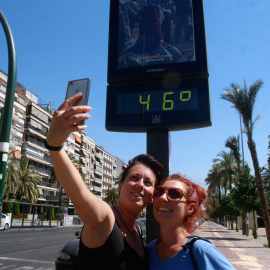 Dos mujeres se fotografían en Córdoba con un termómetro que marca 45 grados en la ciudad. EFE