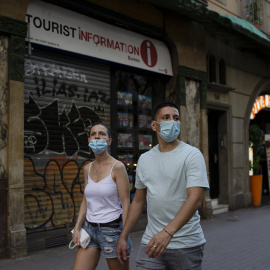 Una parella passa per davant d'una oficina de turisme tancada, a Barcelona. LAIA ROS