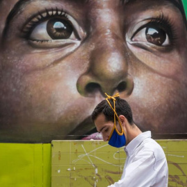 Un hombre con una mascarilla camina frente a un mural este martes en Caracas, Venezuela. /MIGUEL GUTIÉRREZ / EFE