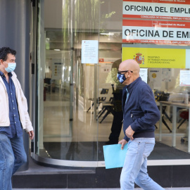 Dos personas con mascarilla pasan por una oficina de empleo de Madrid. E.P./Marta Fernández