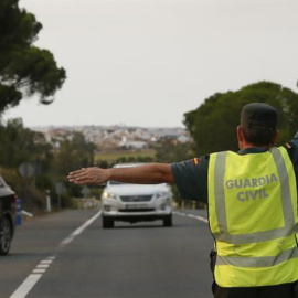 Un Guardia Civil desvía el tráfico tras el corte de la carretera de acceso a la localidad de Matalascañas, por el incendio de Moguer. /EFE