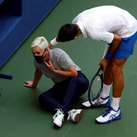 Novak Djokovic de Serbia intenta ayudar a una jueza de línea después de golpearla con una pelota en la garganta durante su partido contra Pablo Carreño en el US Open Tennis. EFE / EPA / JASON SZENES