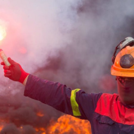 Un trabajador de Alcoa San Cibrao enciende una bengala durante una manifestación / EP