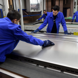 Varios trabajadores preparan una purta corredera para un automóvil en el Centro de Innovación del fabricante de componentes de automóvil Gestamp, en la localidad alemana de  in Bielefeld. AFP/Patrick Stollarz