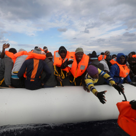 Un voluntario de Proactiva Open Arms acerca un achaleco salvavidas a los inmigrantes que tratan de rescatar en el Mediterráneo.-REUTERS/Yannis Behrakis