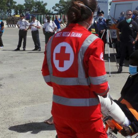 Trabajadores de la Cruz Roja ayudan a desembarcar a los 402 inmigrantes rescatados en el Mediterraáneo a su llegada al puerto de Brindisi (Italia). /EFE