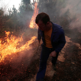 Un hombre apaga las llamas de incendio de Arbo, en Galicia.- REUTERS