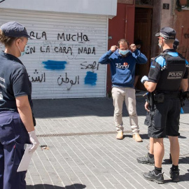 Agentes cívicos (i) y de la Guardia Urbana (d) entregan una mascarilla a un hombre que no llevaba, este jueves, cuando se han puesto en marcha las medidas especiales de restricción de movimientos. /EFE