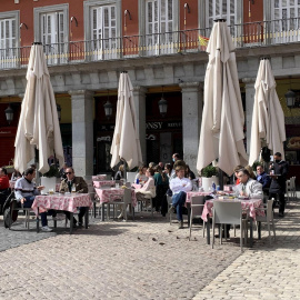 Varios turistas en su mayoría franceses disfrutan del sol en la Plaza Mayor de Madrid.