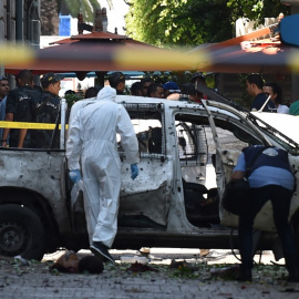 Dos investigadores analizan uno de los vehículos que ha hecho explosión este jueves en la capital de Túnez. /AFP