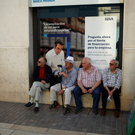 Un grupo de pensionistas sentados en la ventada de una sucursal del banco BBVA en Málaga.