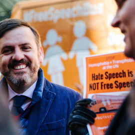 Ignacio Arsuaga, el presidente de "Hazte Oír", habla con los medios mientras un grupo de personas protestan por la presencia del 'Autobús del Odio' en Nueva York. EFE/Alba Vigaray