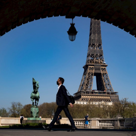 31/03/2021. Un peatón con mascarilla anda por el puente Bir Hakeim cerca de la Torre Eiffel poco antes de que Macron anunciara las nuevas restricciones, este miércoles en París. - EFE