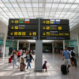 Viajeros junto a uno de los paneles informativos del Aeropuerto Barcelona-El Prat. REUTERS/Albert Gea