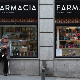 Un hombre mayor sentado en el escaparate de una farmacia en Madrid. REUTERS/Juan Medina