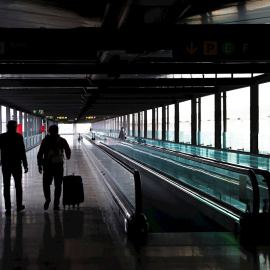 Dos pasajeros cruzan una de las terminales del Aeropuerto Adolfo Suárez Madrid-Barajas.