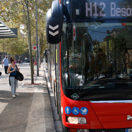 Un bus aturat a la plaça Universitat amb usuaris a la parada.