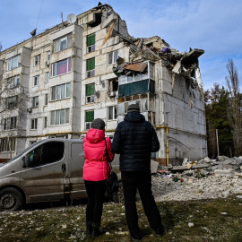 02/12/2022 Dos personas residentes en la zona observan los daños en un bloque de viviendas bombardeado en la ciudad ucraniana de Kluhyno-Bashkyrivka (Járkov)