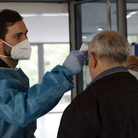 Personal sanitario del SERMAS toma la temperatura a una persona en la entrada de una residencia de mayores.