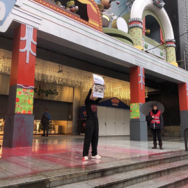 Una activista sostiene una pancarta tras rociar con pintura parte del escenario navideño infantil de Cortylandia.