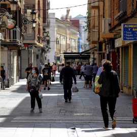 Ciudadanos con mascarillas paseando por una calle de València. /EFE