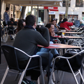 Una cambrera netejant una taula d'una terrassa del bar Las Euras a la plaça de la Vila de Gràcia de Barcelona.