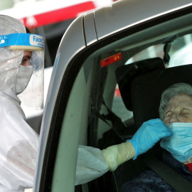 Una sanitaria protegida con EPI toma una muestra para una prueba PCR frente al hospital de Gandía.