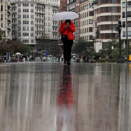 09/04/2021. Una persona se protege de la lluvia con un paraguas este viernes, en València. - EFE